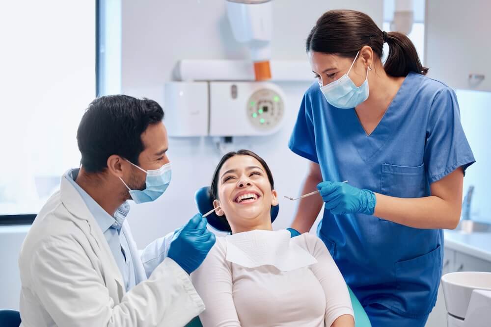 two orthodontists working with smiling patient